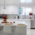 Full of a very modern white kitchen with shaker style cabinets, a large island and solid stone flooring
