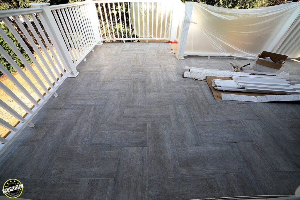 Concrete deck tiling and white vinyl railing